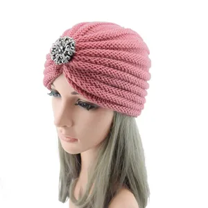 Pink knitted turban hat featuring silver rhinestone accessory, cozy winter beanie.