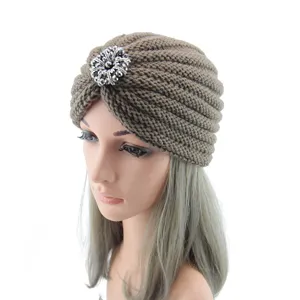 Close-up of the front silver crystal brooch detail on the brown knit turban hat.