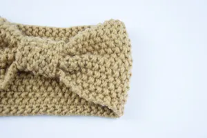 Knitted headband detail shot showcasing the popcorn texture and elegant cross bow design.