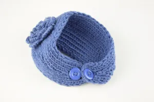 Detailaufnahme eines blauen Strick-Stirnbandes mit Häkelblume und praktischem Knopfverschluss.