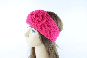Nahaufnahme des kuscheligen warmen rosa Häkelstirnbands mit süßem Blumenmuster.