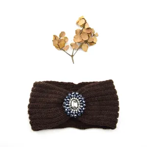 Close-up of a dark brown knitted headband featuring a sparkling rhinestone gem flower detail.