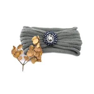 Vista dettaglio fascia in maglia grigia, elegante accessorio per capelli con gemma di cristallo.