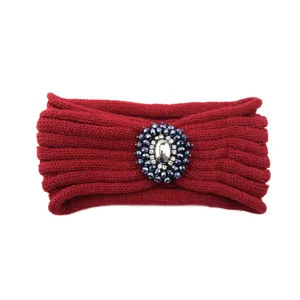 Dettaglio di una fascia lavorata a maglia rossa con scintillante spilla floreale in strass.
