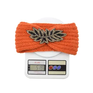Orange knit headband detail showing weight and beaded leaf embroidery craftsmanship.