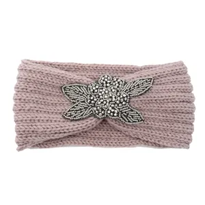 Handmade knitted wool headband with beaded floral embellishment, warm winter hair accessory.