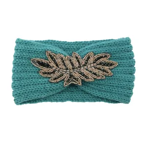 Handmade knitted headband with beaded leaf embellishment, warm winter hair accessory.