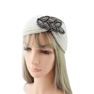 Detailed view of white knitted wool headband featuring black rhinestone leaf embellishment.