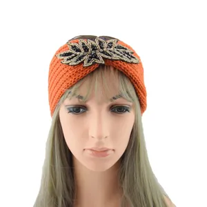 Orange knitted headband detail, handmade black and gold beaded leaf accent for winter warmth.