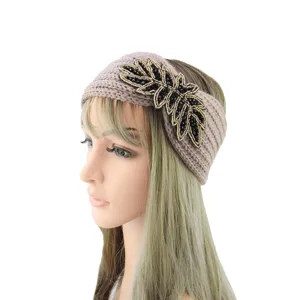Close-up detail of the handmade black beaded leaf embellishment on the cozy knitted hairband texture.