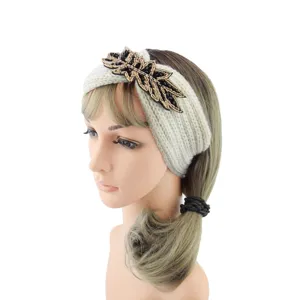 Close-up side view of a white knitted headband with black and gold beaded leaf detail.