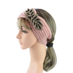 Handcrafted pink knitted headband with black beaded leaf decoration, warm winter hair accessory.