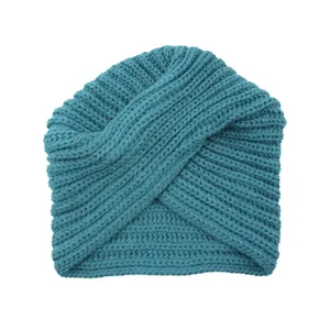 Detailed close-up of a blue-green knitted turban beanie featuring unique cross texture.