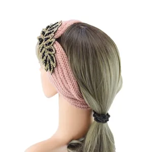 Detailed view of pink knitted headband with black and gold beaded crystal leaf applique.
