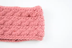 Close-up detail of a pink cable knit headband, warm winter ear warmer hair accessory.