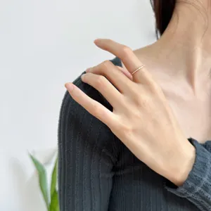Gros plan détaillé d'une bague géométrique ultra fine et minimaliste portée sur la main.