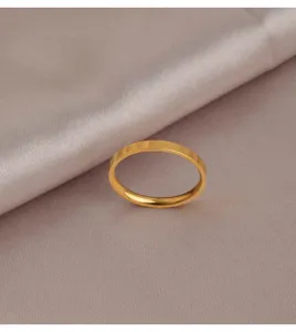 Gros plan détail d'un anneau minimaliste en acier titane doré avec motifs de cœurs gravés.