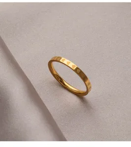 Détail de bague cœur en acier inoxydable, finition dorée brillante, motif délicat.