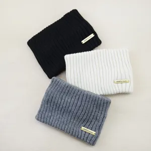 Close-up detail of soft knitted winter headbands in black white and grey with metal tag