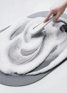 Grey bathroom floor mat with cleaning brush and soap foam detail view, water absorbent non-slip.