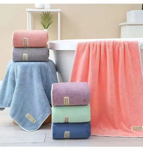 Close-up detail of soft coral fleece bath towels in assorted solid colors for bathroom use.