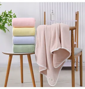 Detail view of soft coral fleece bath towels with braided edge, stacked and draped neatly.
