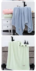 Suave y absorbente toalla de baño de velur de coral con bordes ribeteados y etiqueta.