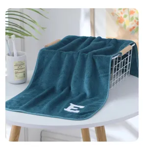Detailaufnahme eines dicken Korallenfleece Handtuchs mit besticktem Buchstaben E im Bad.