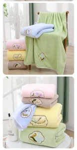 Detailansicht des weichen Korallenfleece-Handtuchsets mit süßer Blumenstickerei in Pastellfarben.