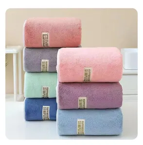Close up detail view of rolled coral fleece bath towels in multiple soft colors and styles.