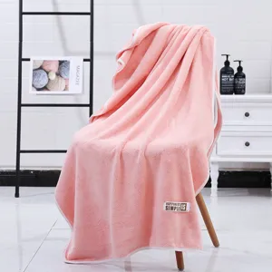 Gran toalla de baño de felpa coral rosa gruesa con borde y etiqueta para un uso hogareño muy cómodo.