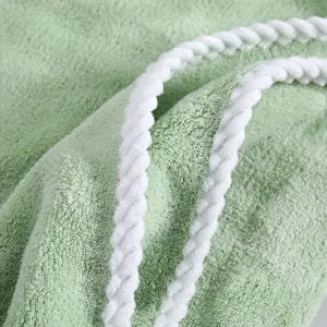 Soft coral fleece bath towel with white braided binding, absorbent thick plush material.