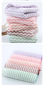 Detailed view of soft coral fleece wave towels, absorbent face wash cloth stack and rolls.