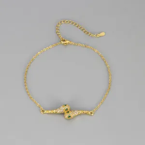 Vue détaillée de chevillère serpent plaquée or avec cristaux pavés et accents de pierre verte.