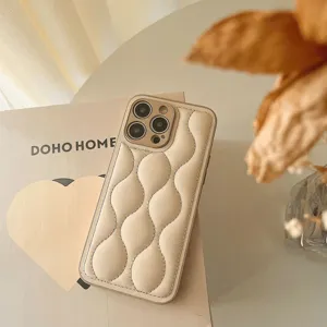 Detail shot of beige quilted puffer phone case with wavy design and soft leather texture.