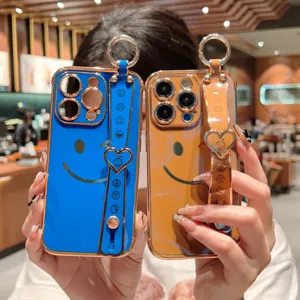 Vue détaillée des coques iPhone de luxe avec dragonne et design de visage souriant mignon.