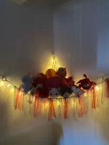 Handmade woven cotton rope toy hammock for kids room corner with colorful ribbons and lights.