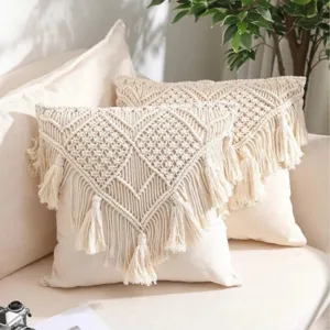 Detailed shot of handmade macrame throw pillow cover with bohemian fringe tassels, beige color.