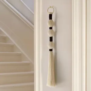 Gedetailleerd overzicht handgemaakte macramé wandhanger, garenballen en kwast voor boho decoratie.