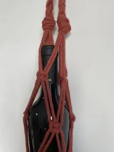 Gros plan sur le détail du sac filet porte bouteille de vin en macramé de coton fait main et tissé.
