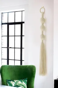 Handgemaakte katoenen macrame wandkleed met ballen en kwastjes voor boho slaapkamer decor.