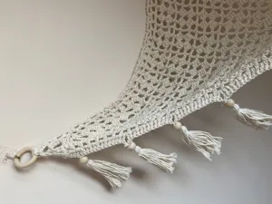 Primo piano di un'amaca per giocattoli in macramè fatta a mano con anelli di legno e nappe.