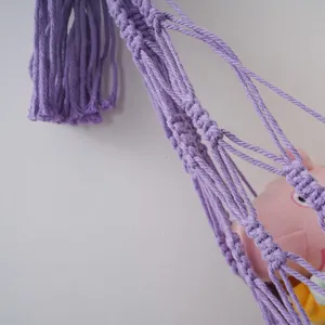 Gedetailleerde close-up van de paarse handgemaakte macramé speelgoed hangmat met fijne knopen.