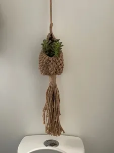 Handmade woven jute hanging teardrop basket detail showing bohemian plant holder and tassel decor.
