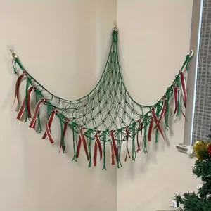 Green handmade macrame toy hammock with red white ribbons, corner wall hanging for kids room.