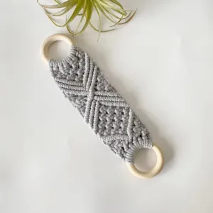 Handmade macrame hanging strap detail close up with natural wooden rings and gray cord.