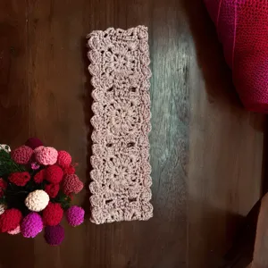Close-up view of the handmade crochet hollow headband detail, showing soft dusty pink yarn work.