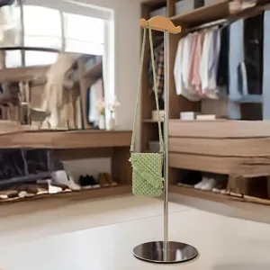 Vue détaillée d'un mini sac à bandoulière tressé vert suspendu sur un support dans l'armoire.
