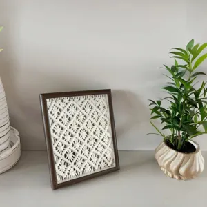 Handmade macrame woven tapestry in a dark wood frame for desktop decor detail shot