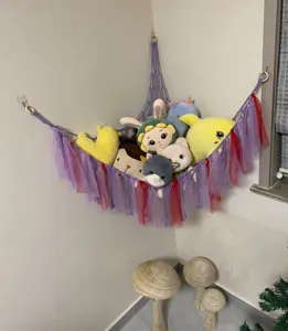 Handmade cotton rope toy hammock with colorful ribbons for kids room corner storage.